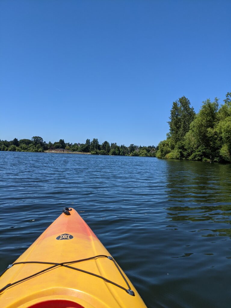 A picture of the front section of a kayak and water from kayaking on Green Lake in Seattle, WA.