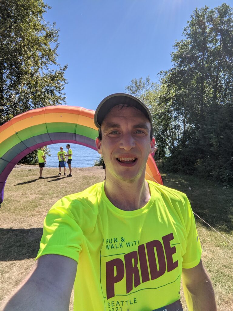 The author in front of a blow-up rainbow, celebrating the end of the Seattle Run & Walk with Pride race